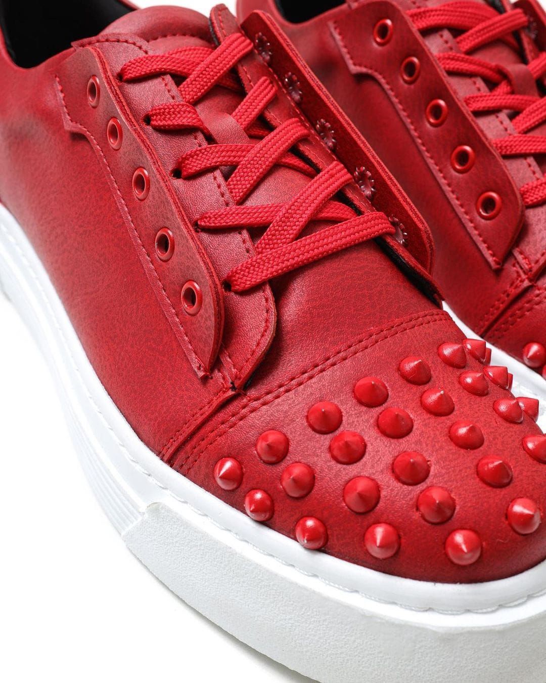 Un par de zapatillas rojas con tachuelas rojas.