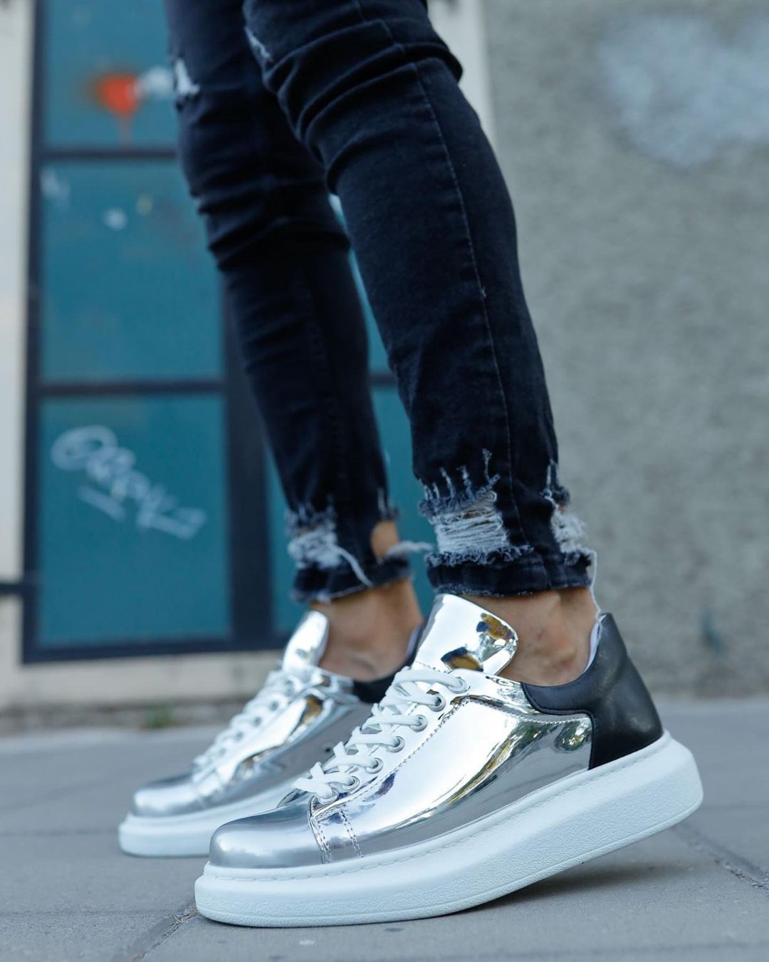 Una persona que lleva un par de zapatillas plateadas y negras.