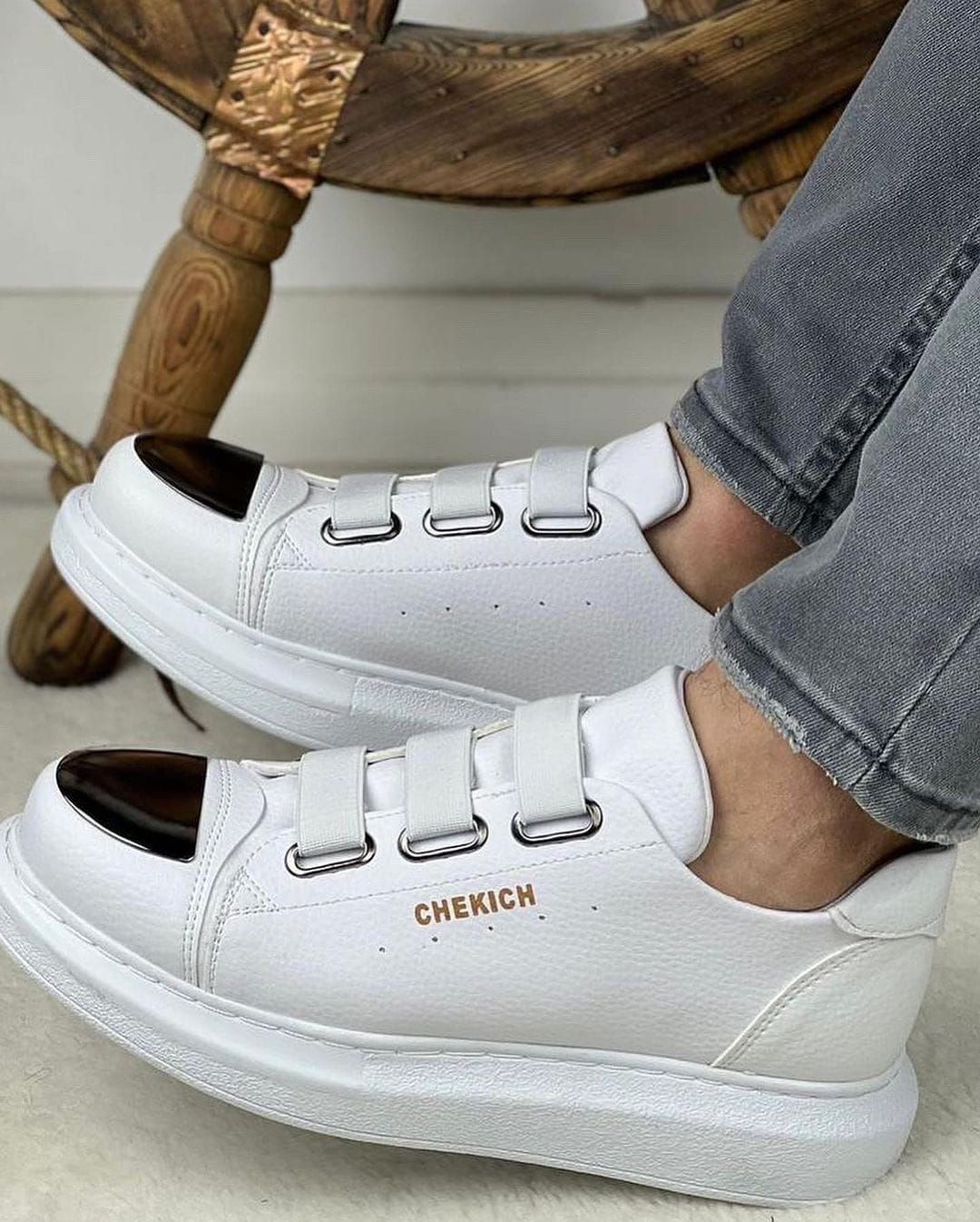 Una persona lleva un par de zapatillas blancas con puntera negra.