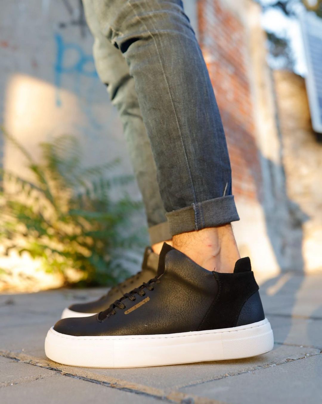 Una persona que lleva un par de zapatillas negras con suela blanca.