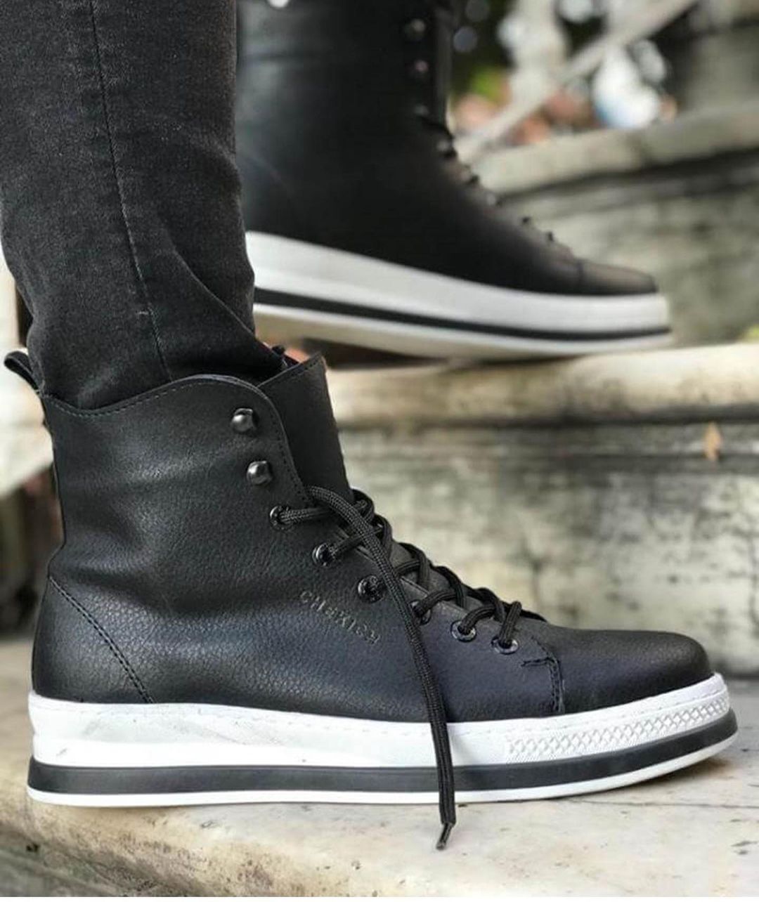 Una persona lleva un par de zapatillas negras de caña alta.