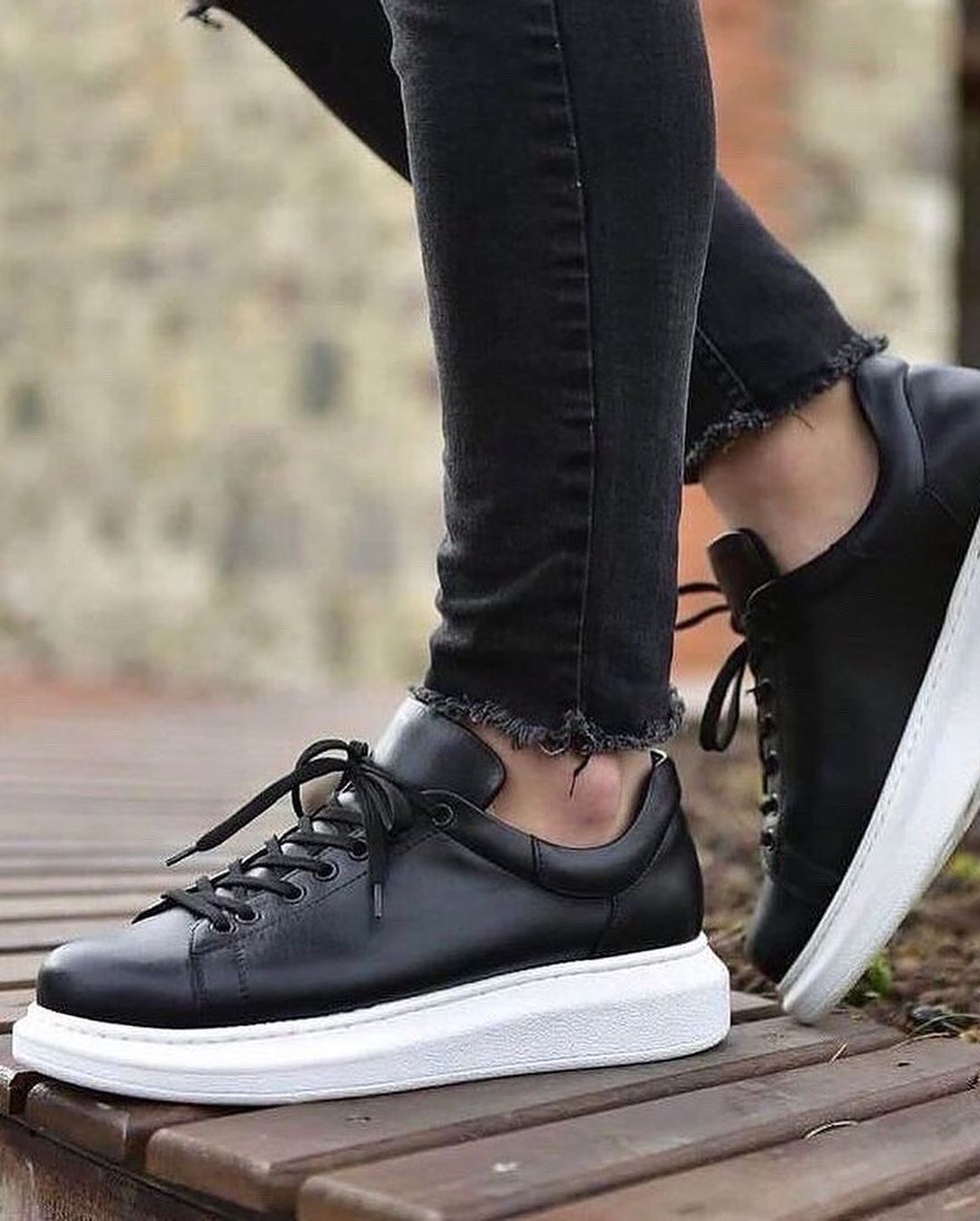 Una persona lleva un par de zapatillas negras con suela blanca.