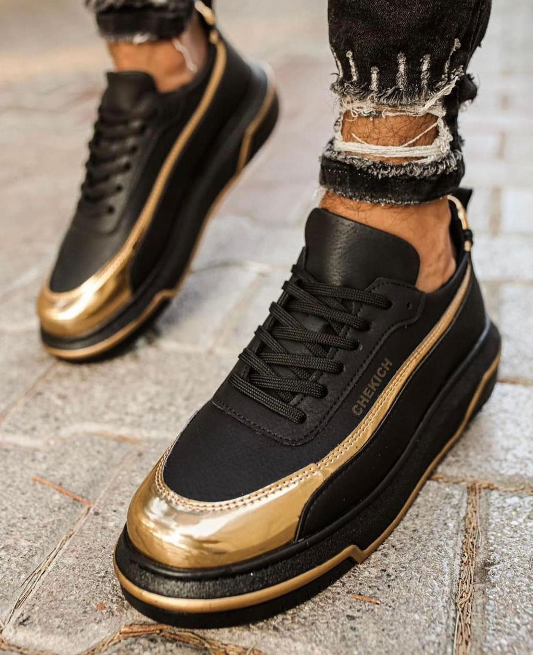 Un par de zapatillas negras y doradas en los pies de una persona.