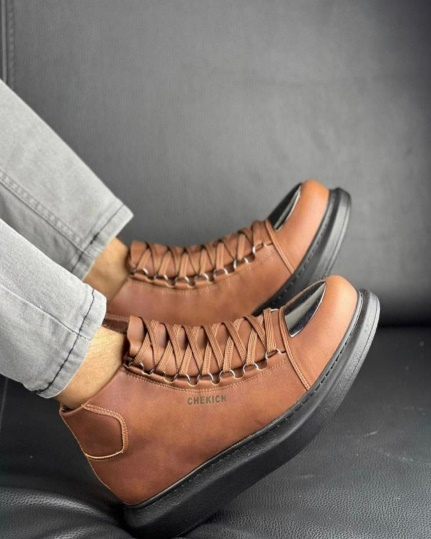 Una persona lleva un par de zapatos marrones en un sofá.