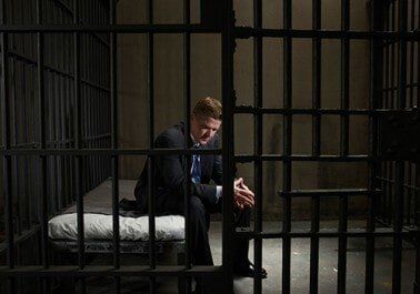 Mature businessman sitting on bed in prison cell - Bail Bonds in Houston, TX Mature businessman sitting on bed in prison cell - Bail Bonds in Houston, TX