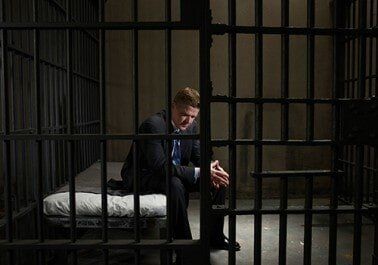Mature businessman sitting on bed in prison cell - Bail Bonds in Houston, TX