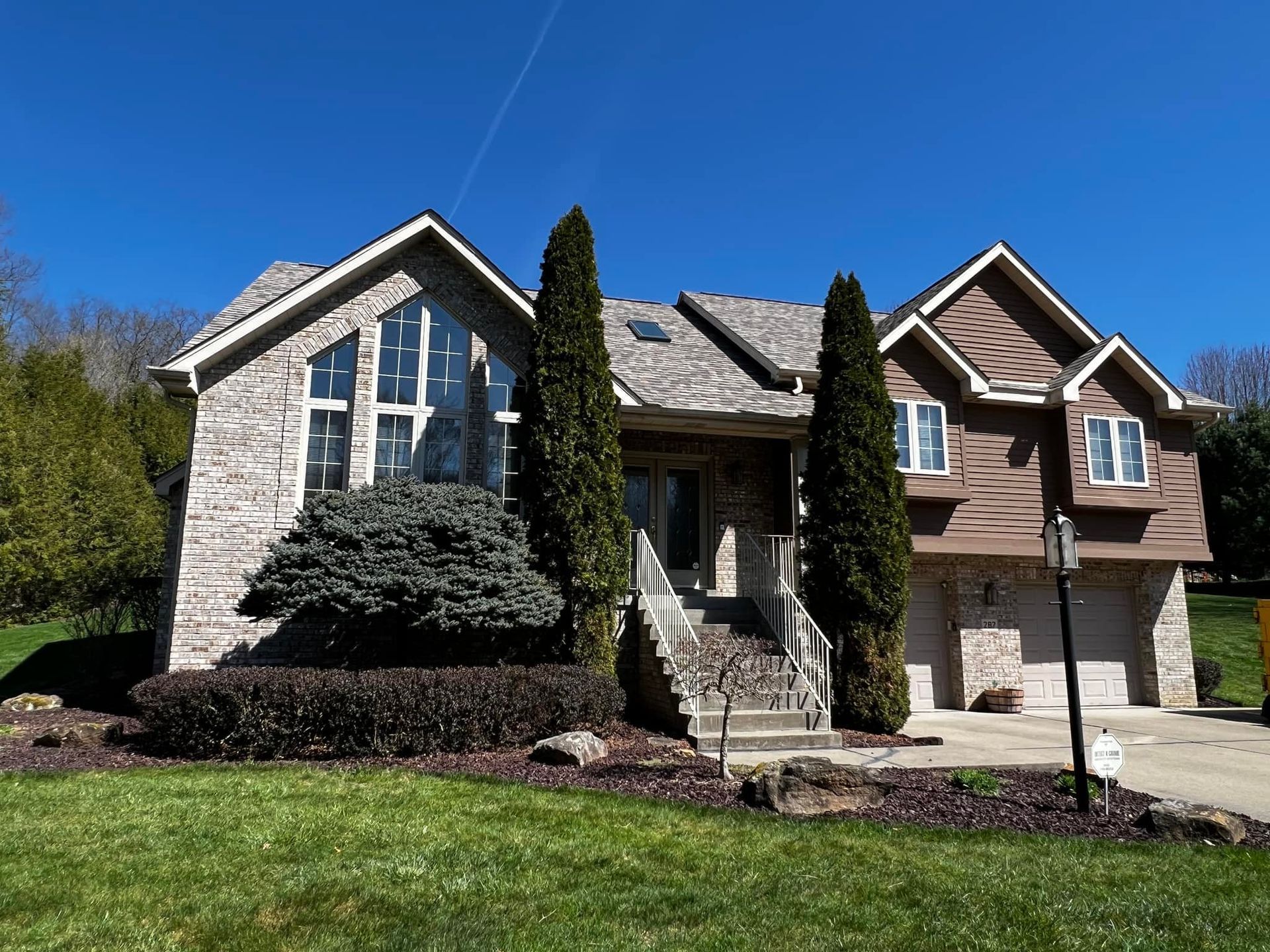 Three connected houses with visible utility pole and power lines against a clear blue sky.