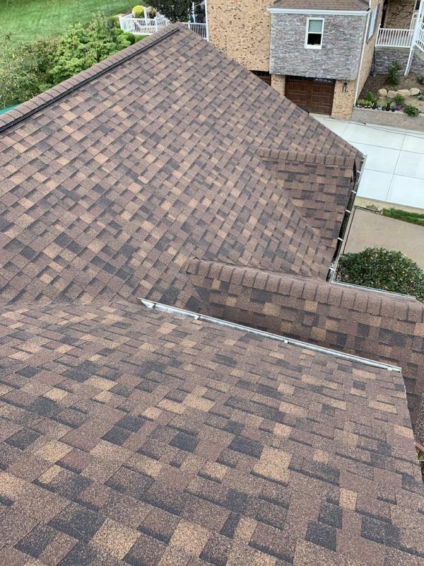 Brown and dark shingles on a residential roof, seen from above.