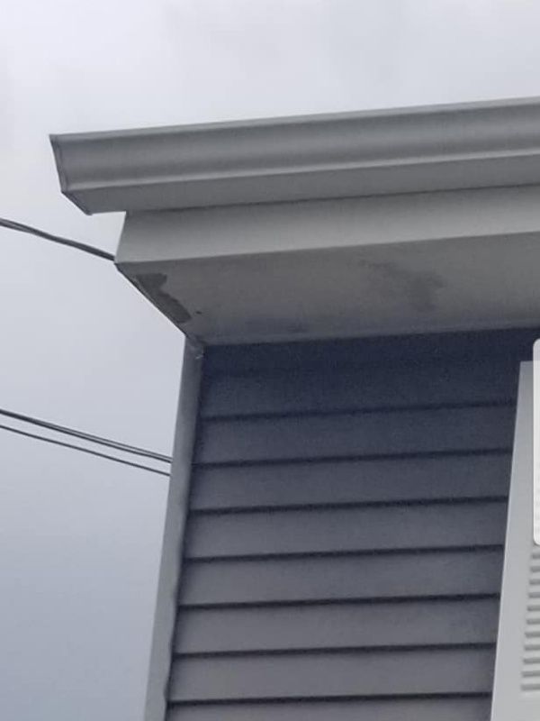 Gray house siding and soffit with white trim and gutter. Electrical wires visible.