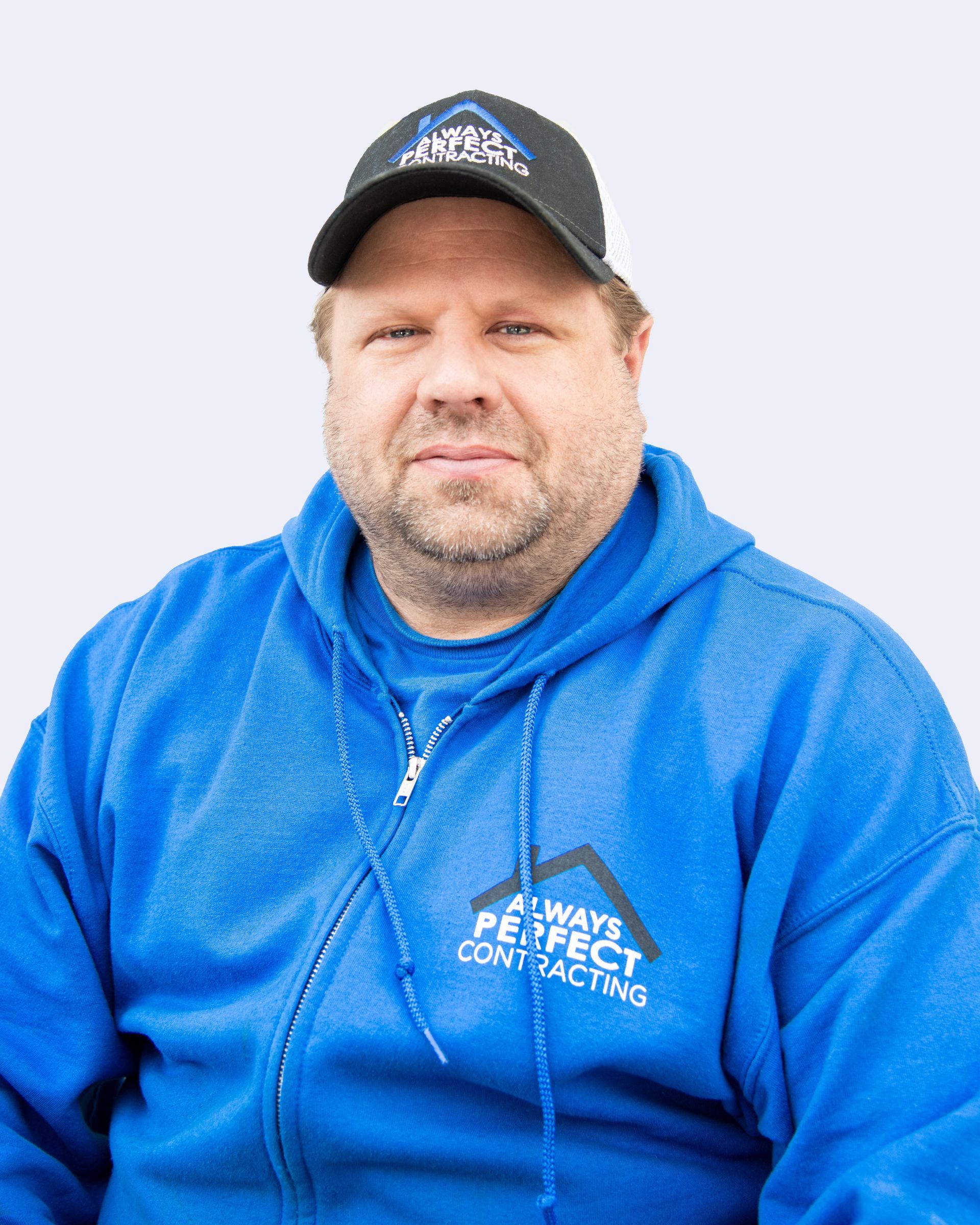 A person with a beard wearing a blue hoodie and black cap, both featuring the 