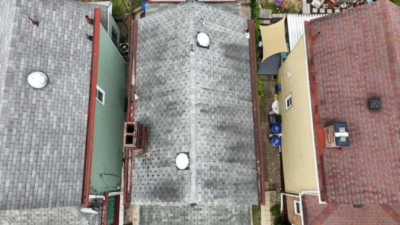 Overhead view of several row houses with dark gray, weathered shingle roofs.