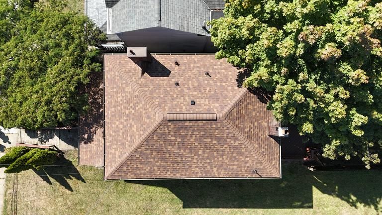 Row of houses with gray roof, white siding, and brick facade on a cloudy day.