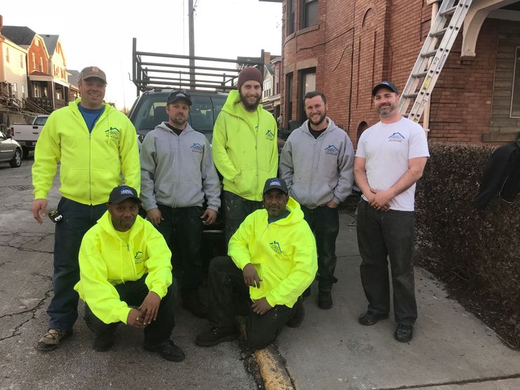 Gray siding, white shutters, window, and damaged white trim under the gutter.