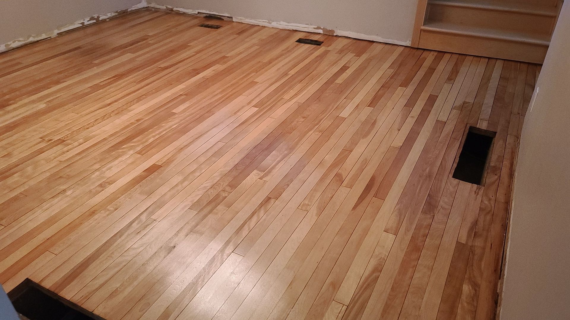 A wooden floor with a hole in the middle of it in a room.