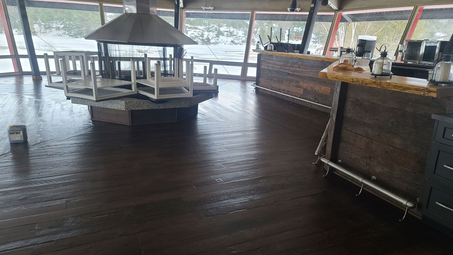 A large empty room with a wooden floor and a bar.