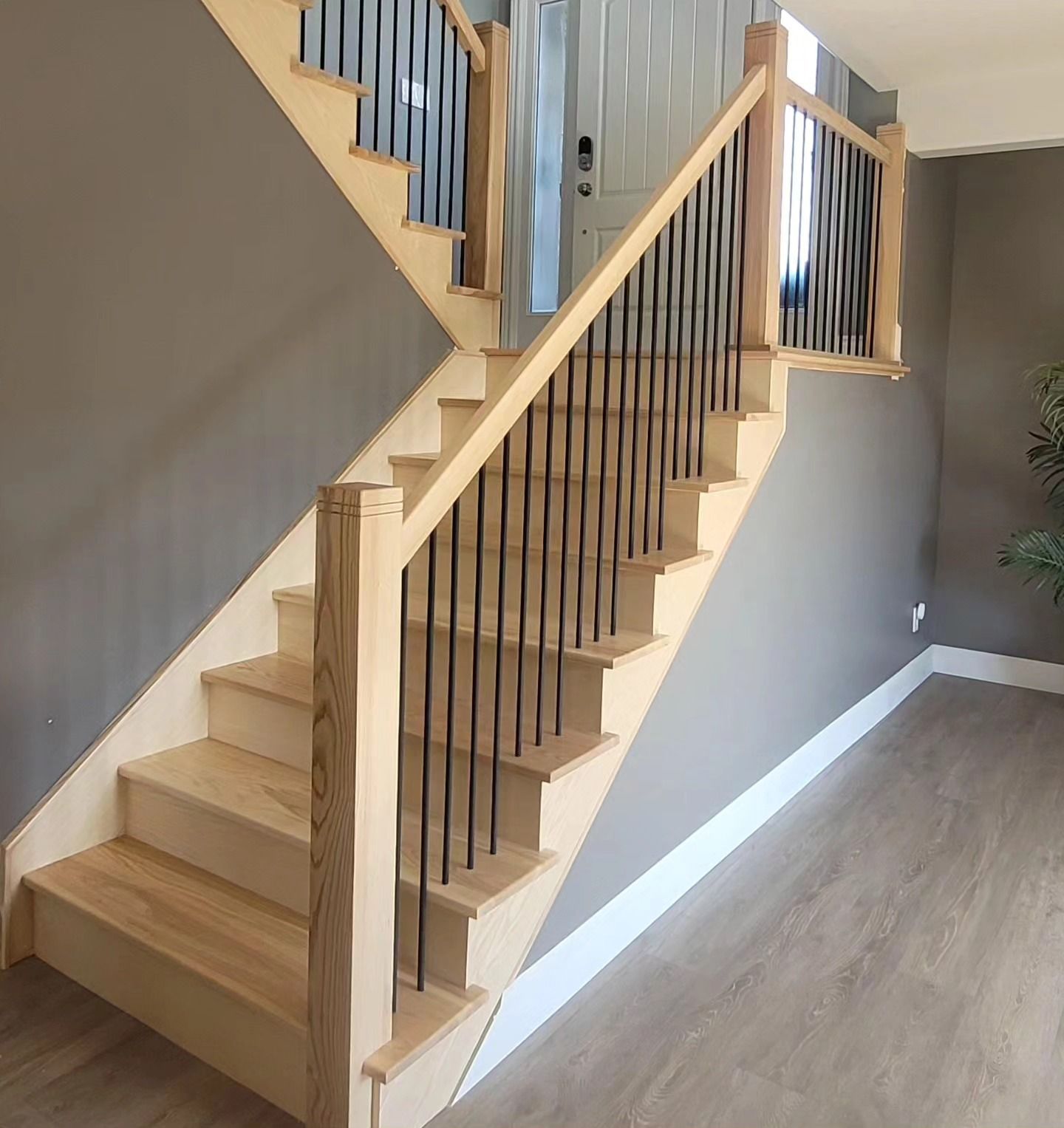 A wooden staircase with a metal railing in a hallway.