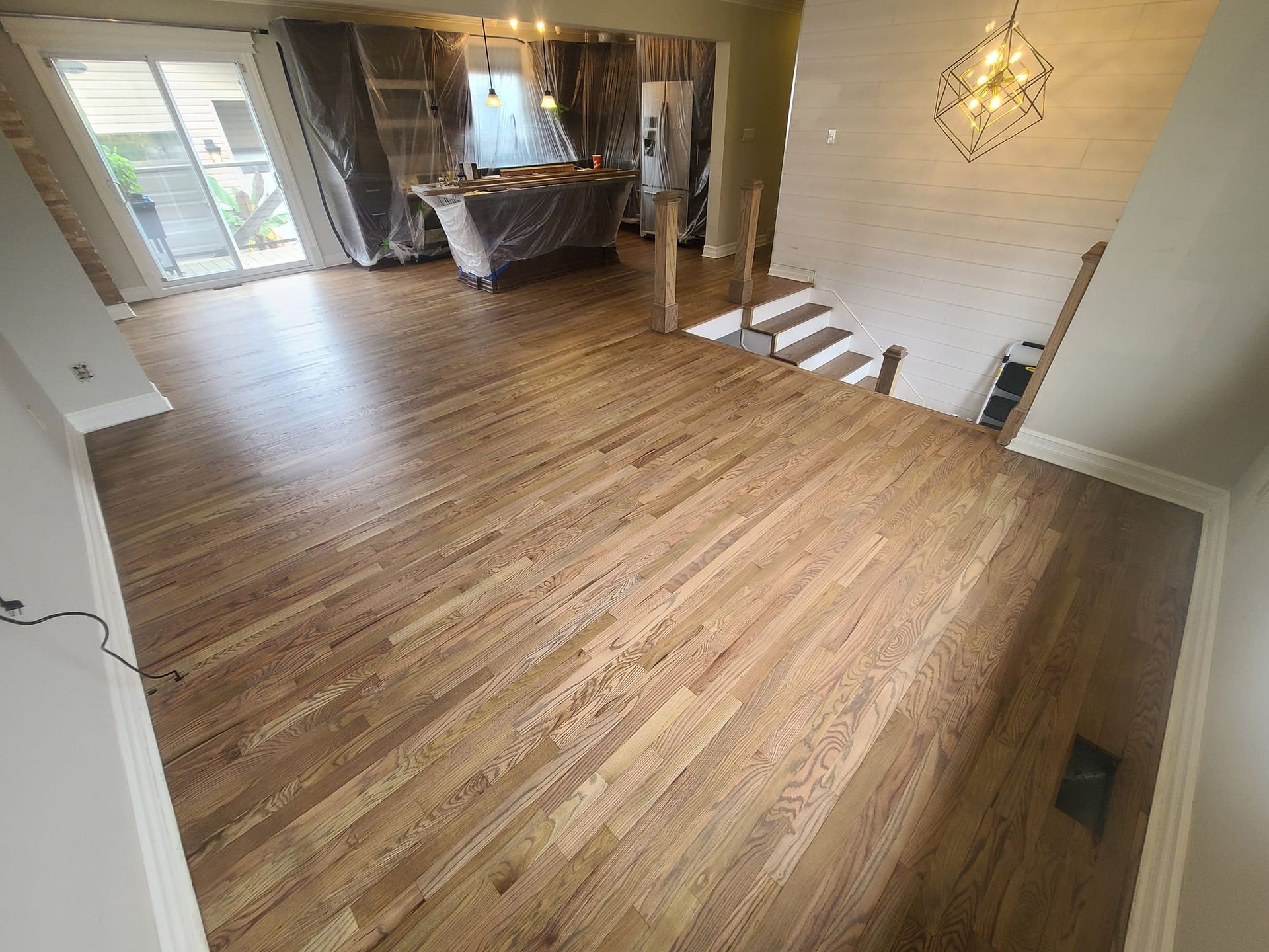 A living room with hardwood floors and stairs in a house.