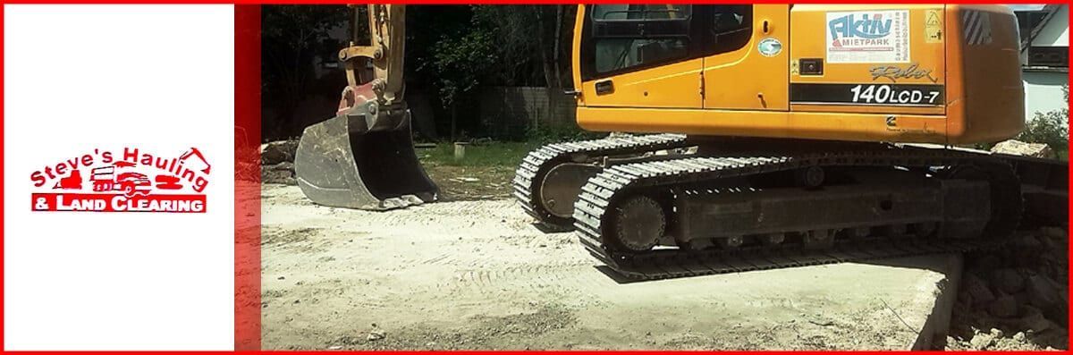 A yellow excavator is driving down a dirt road.
