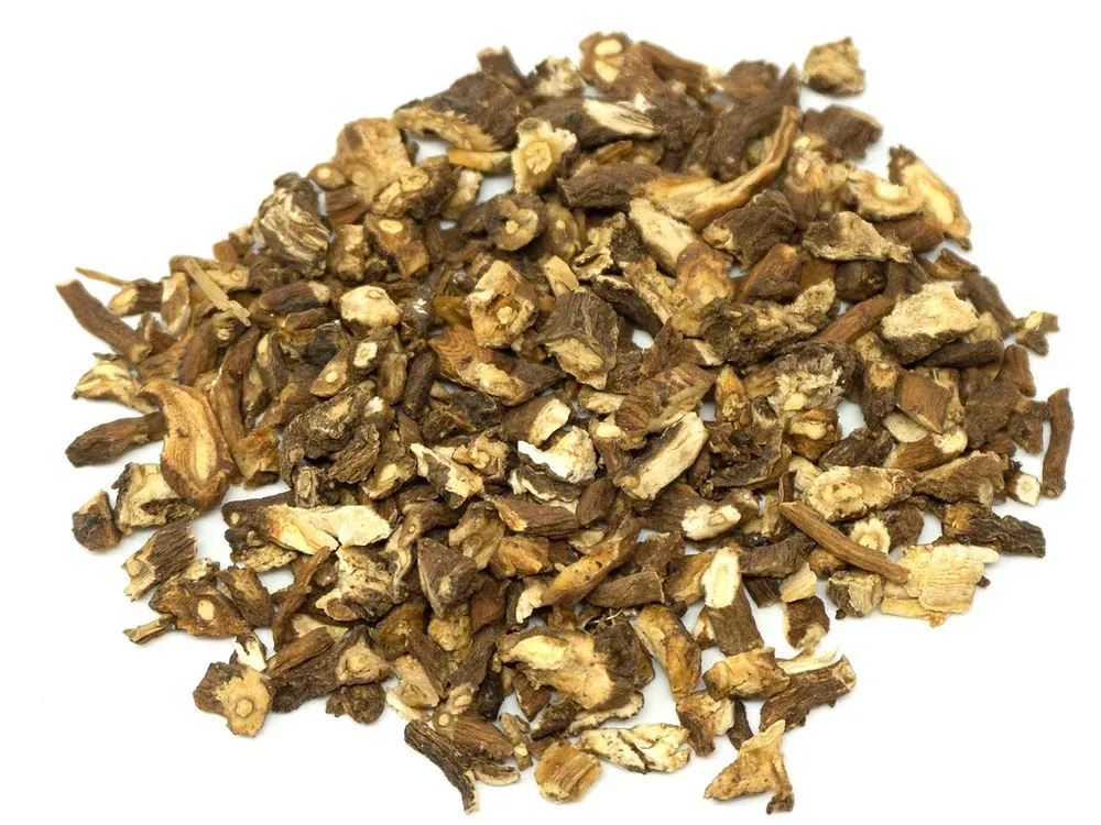 A pile of dried dandelion roots on a white surface.