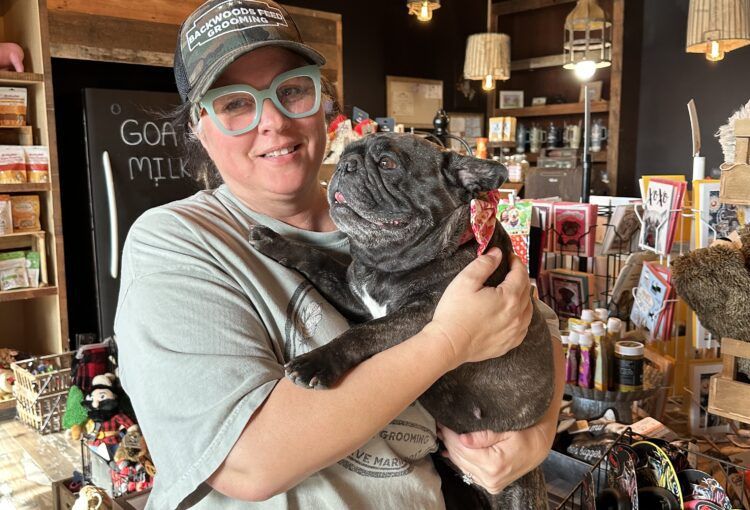 A woman is holding a dog in her arms in a store.