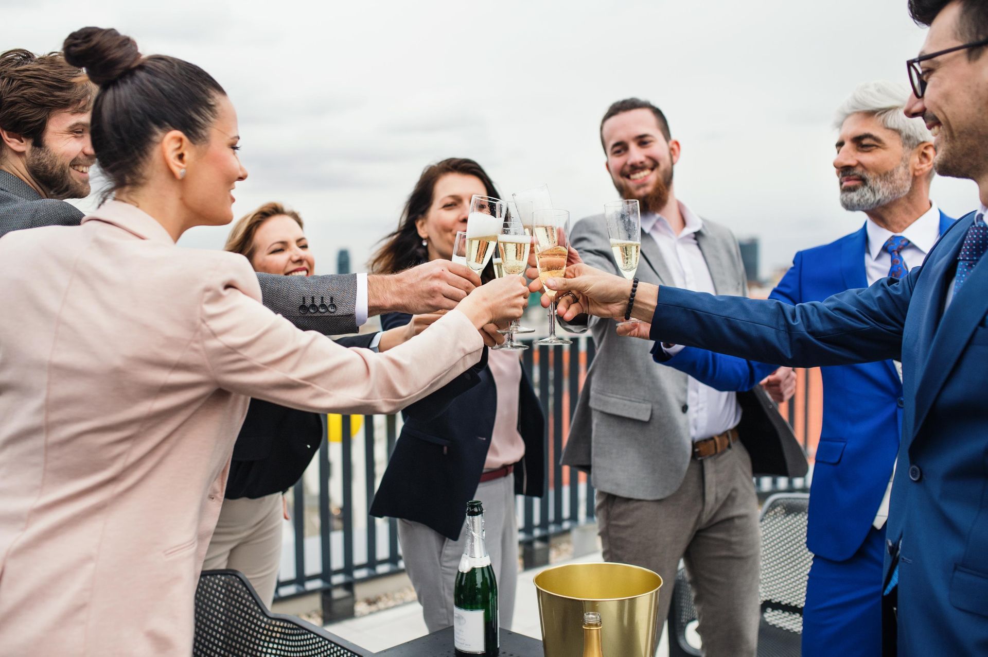 People toasting with champagne on a rooftop, sunny day.