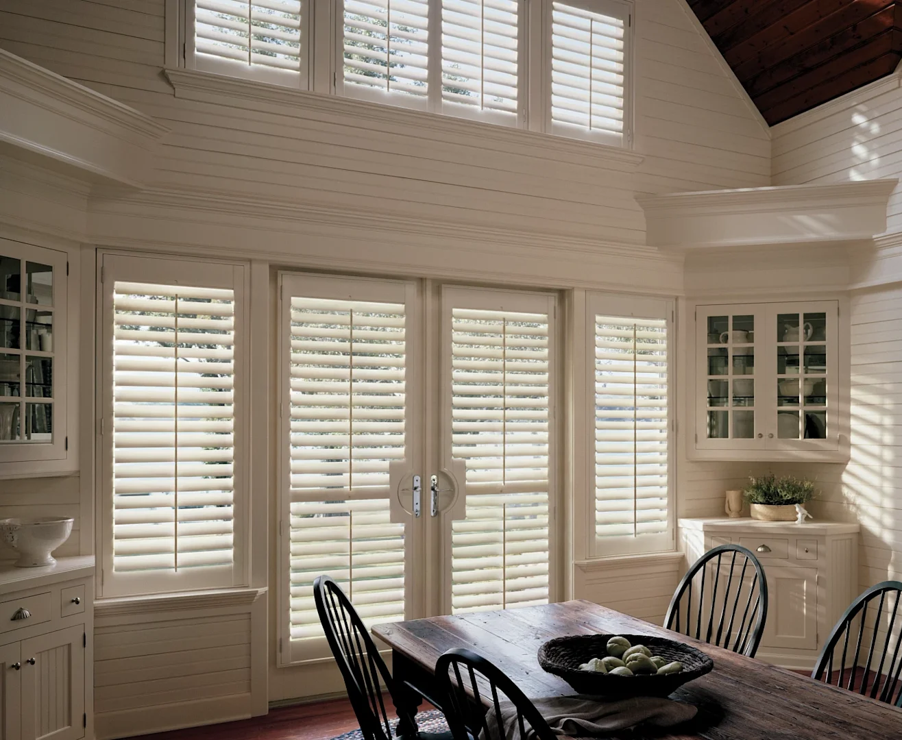 Furnished modern dining room with composite shutters on French doors and adjacent windows.