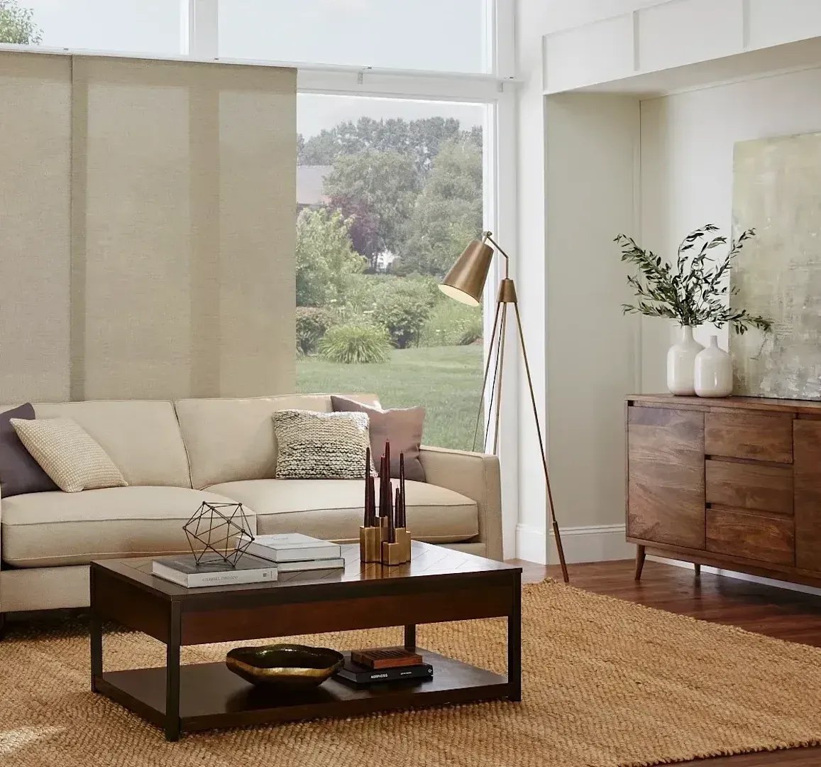 Roller shades in a living room with sofa, accent chairs, and wood furniture.