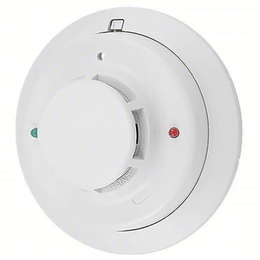 A white smoke detector with a red light on it.