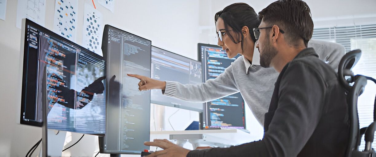 A man and a woman are looking at a computer screen.