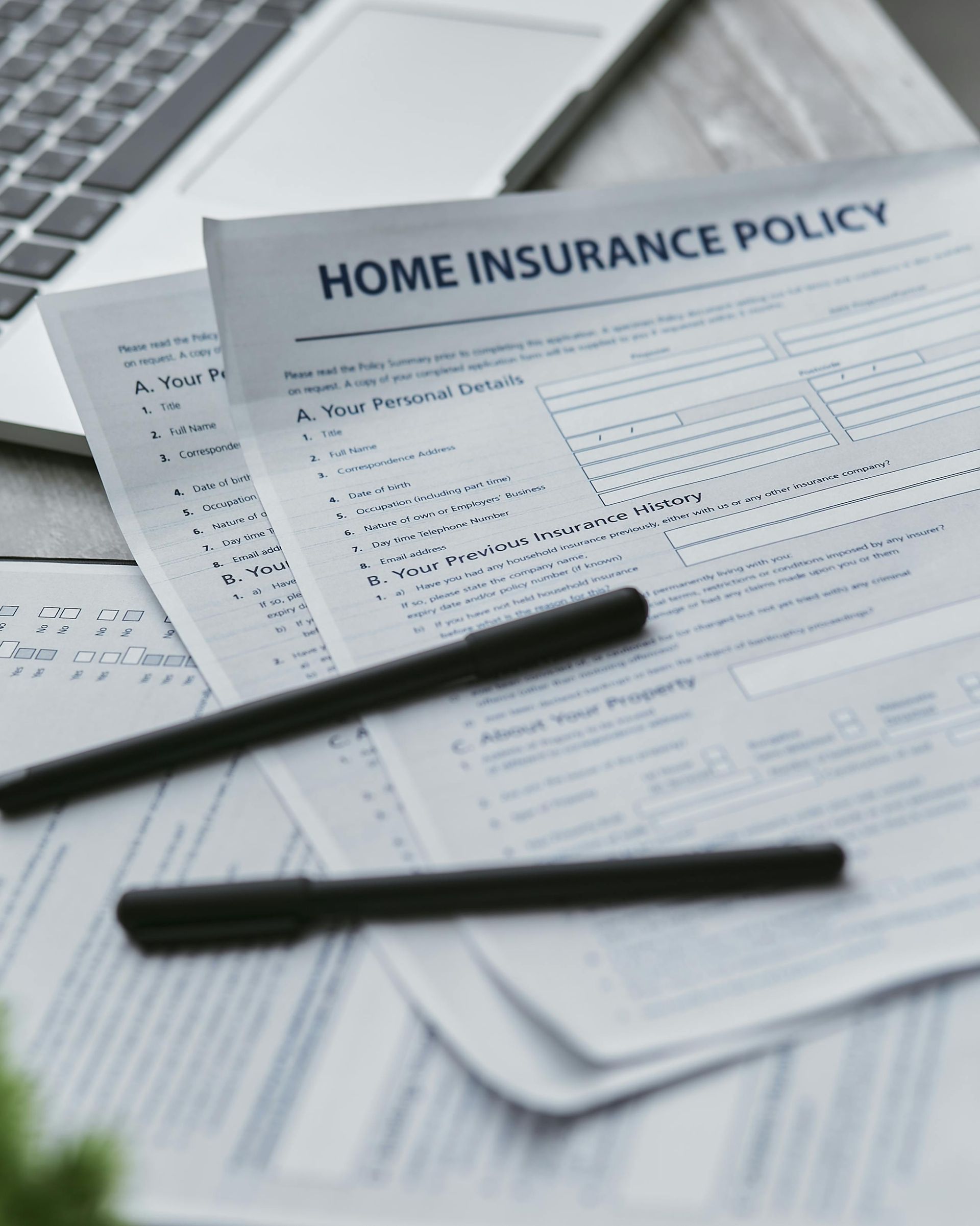 A home insurance policy is sitting on a table next to a laptop.