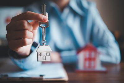 A person is holding a key with a house keychain.