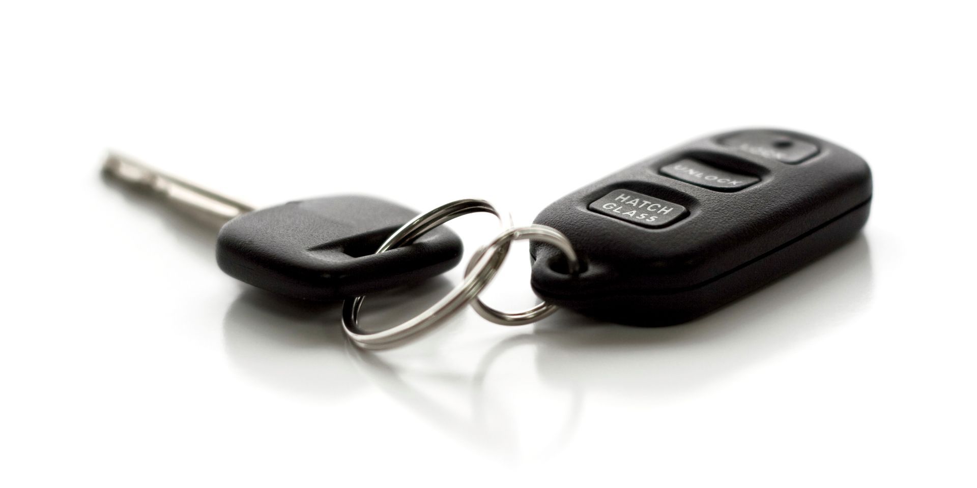 A pair of car keys sitting on top of each other on a white surface.