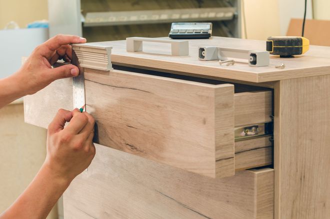 A person is opening a drawer on a wooden dresser.