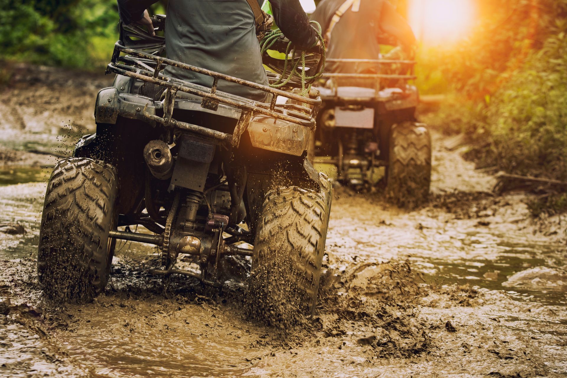 A man is riding an atv through a muddy field