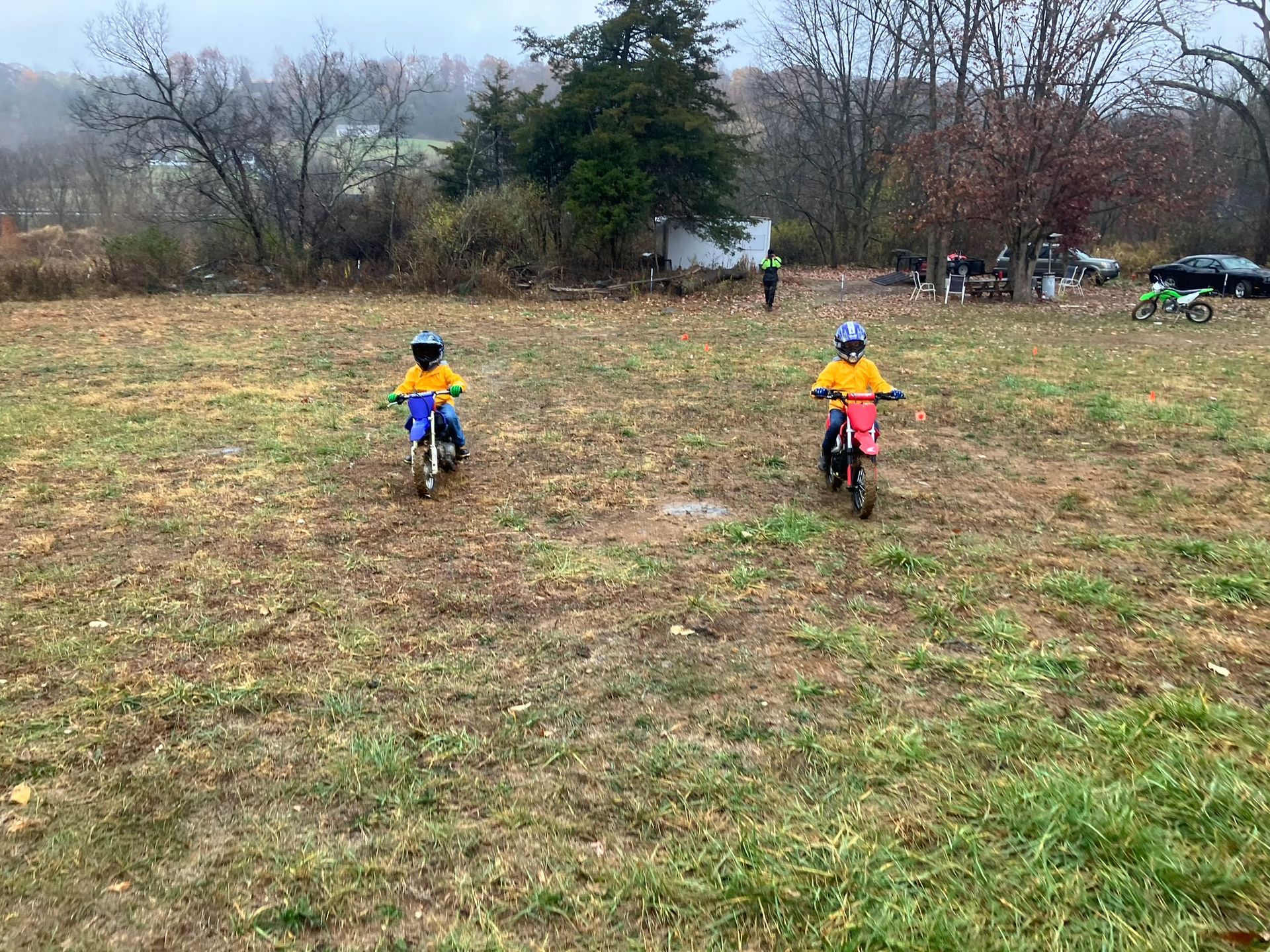 Two young boys are riding dirt bikes in a field