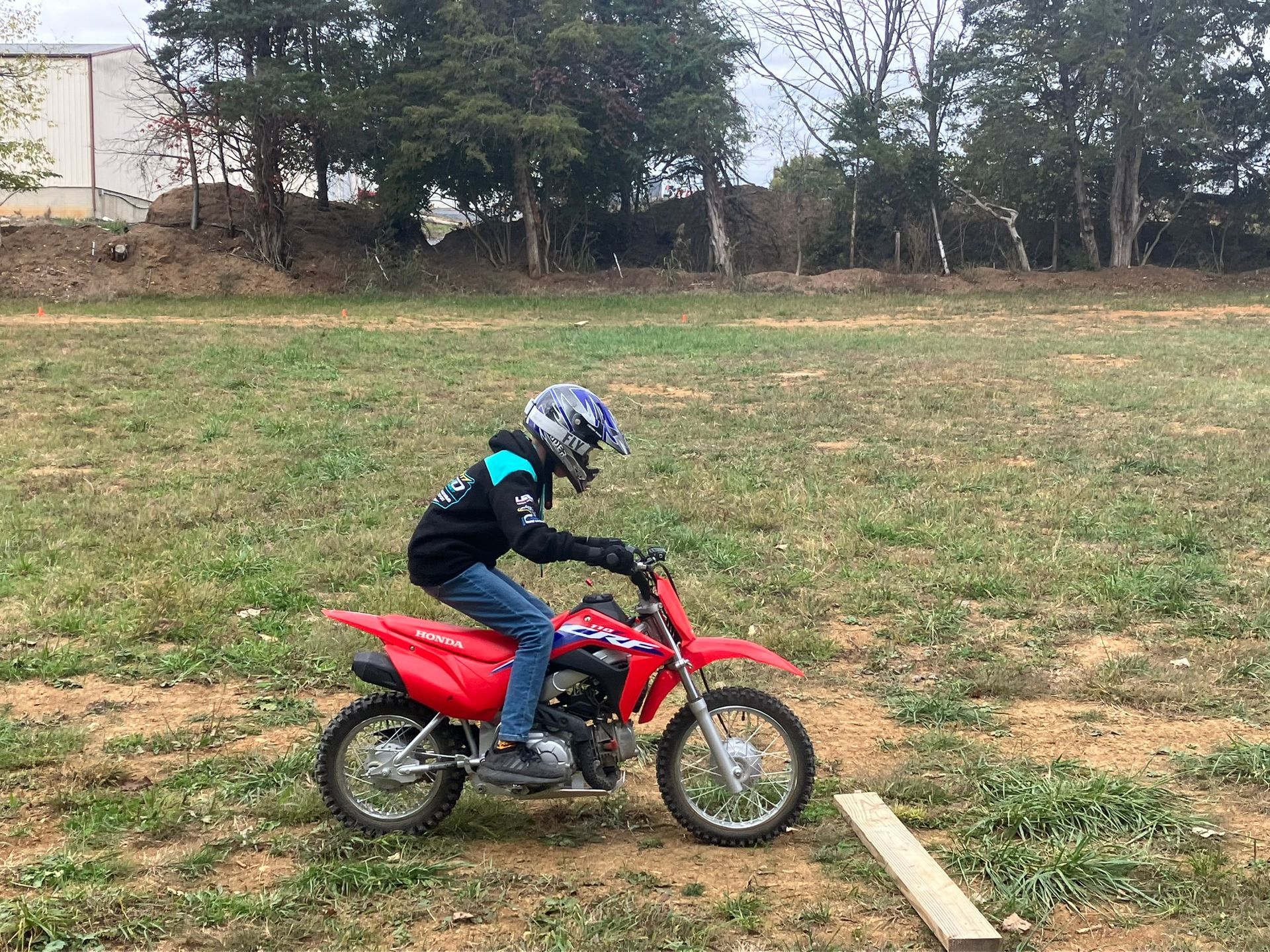 A young boy is riding a dirt bike in a field