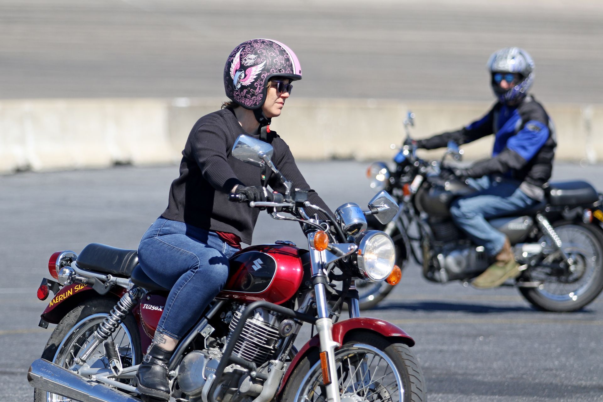 A man and a woman are riding motorcycles on a road