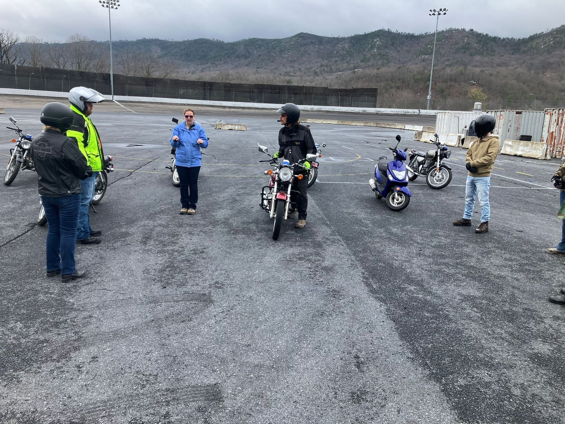 A group of people are standing around motorcycles in a parking lot