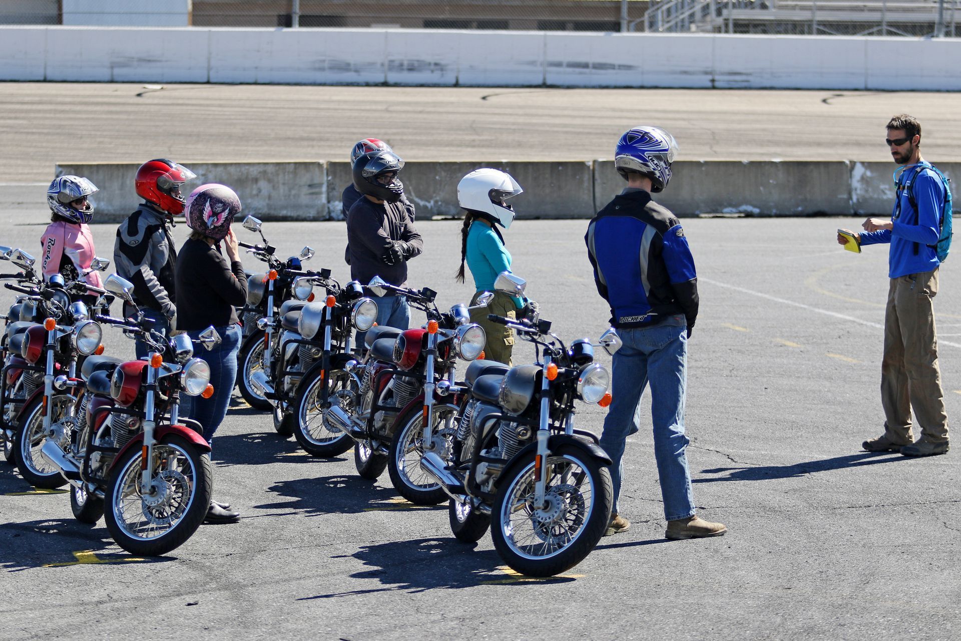 A group of people standing next to motorcycles in a parking lot