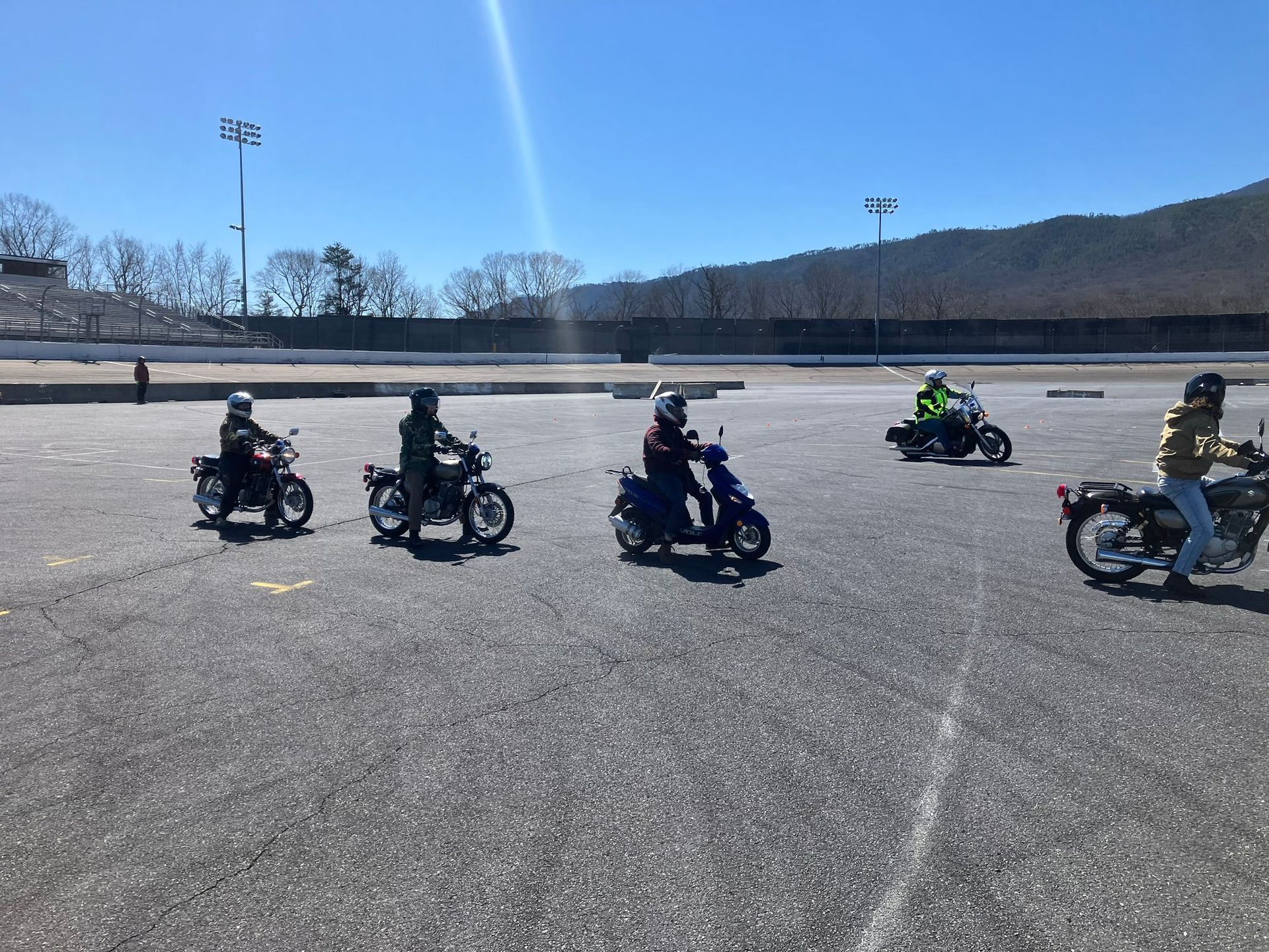 A group of people are riding motorcycles in a parking lot