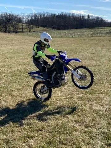 A person is doing a trick on a dirt bike in a field