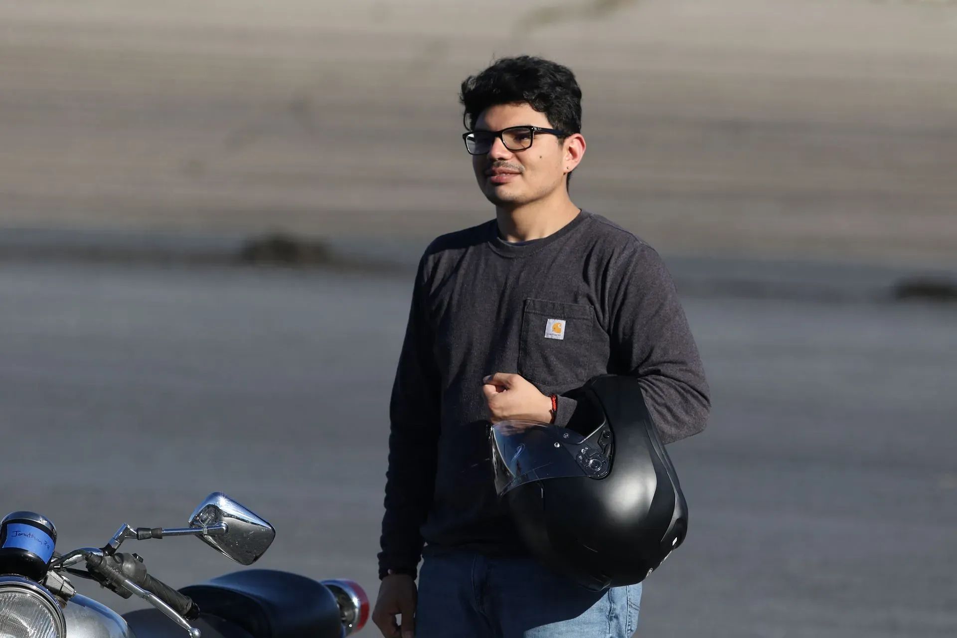 A man is holding a helmet while standing next to a motorcycle