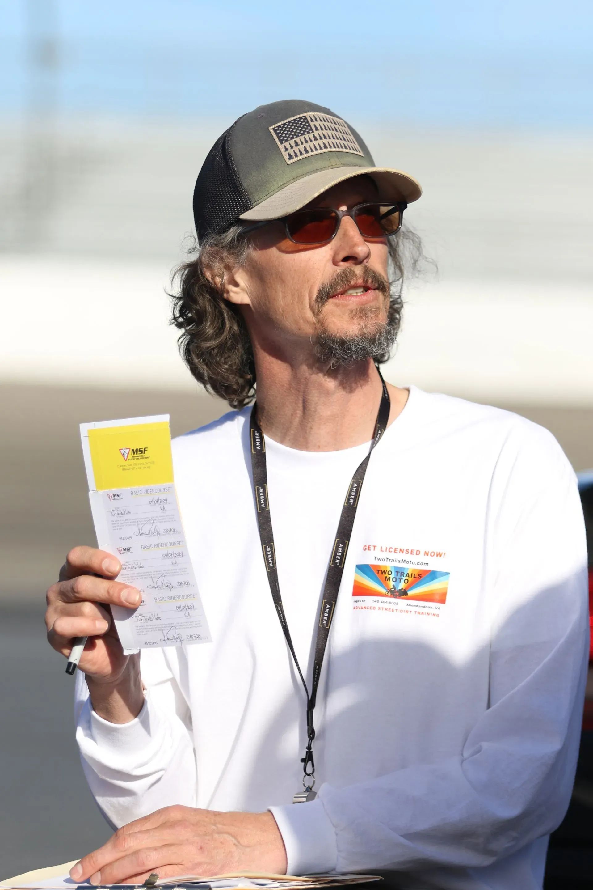 A man wearing a hat and sunglasses is holding a piece of paper