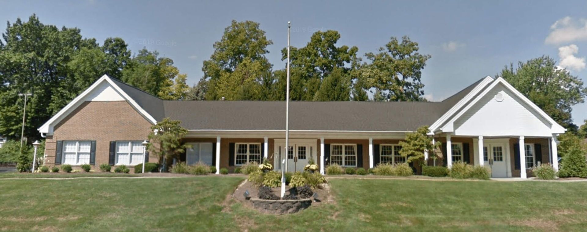 A large brick house with a flag pole in front of it