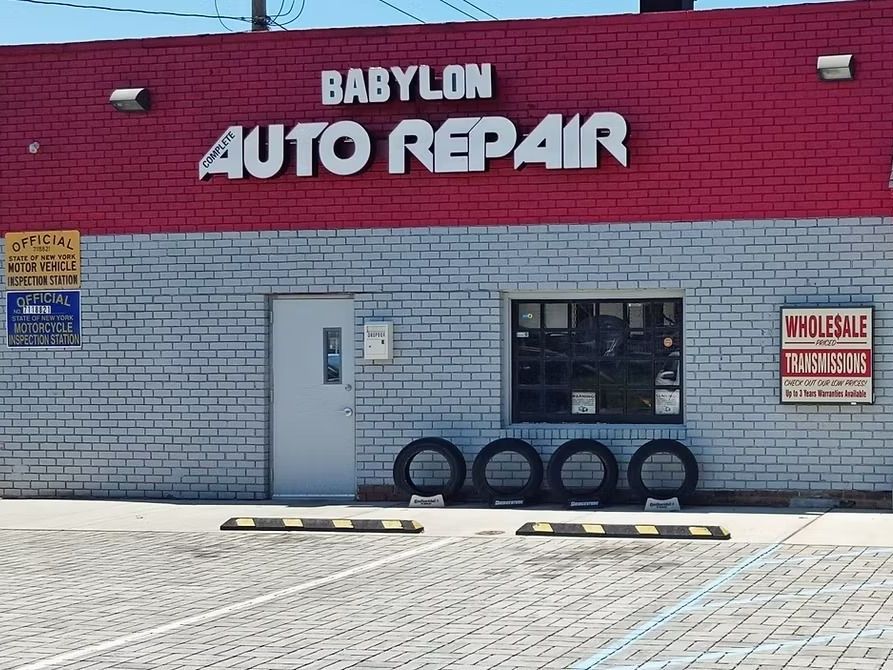 Babylon Auto Repair storefront with red and gray brick, large sign, and tires in front.