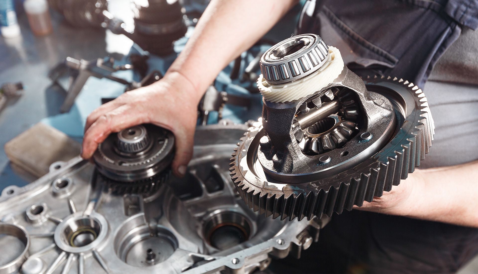 Mechanic assembling car differential parts. Hands hold gears, working inside a metallic engine casing in a shop.