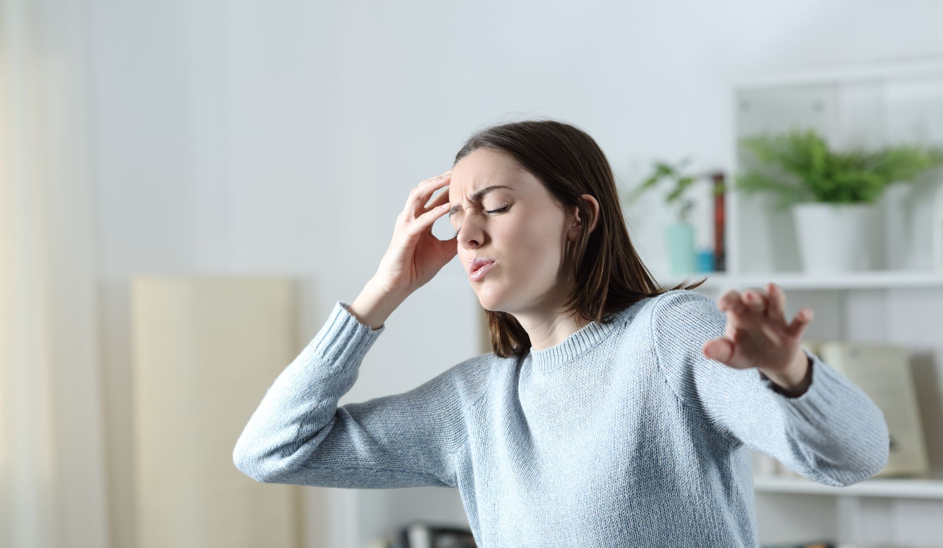 A woman is holding her head because she has a headache.