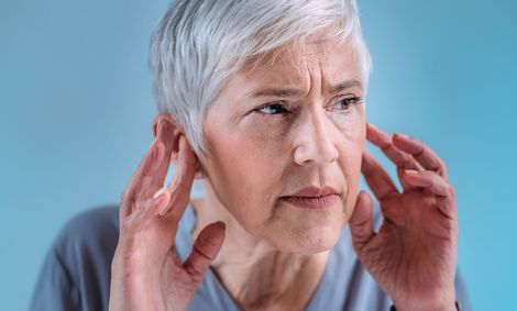 A woman is whispering a secret into an older woman 's ear.
