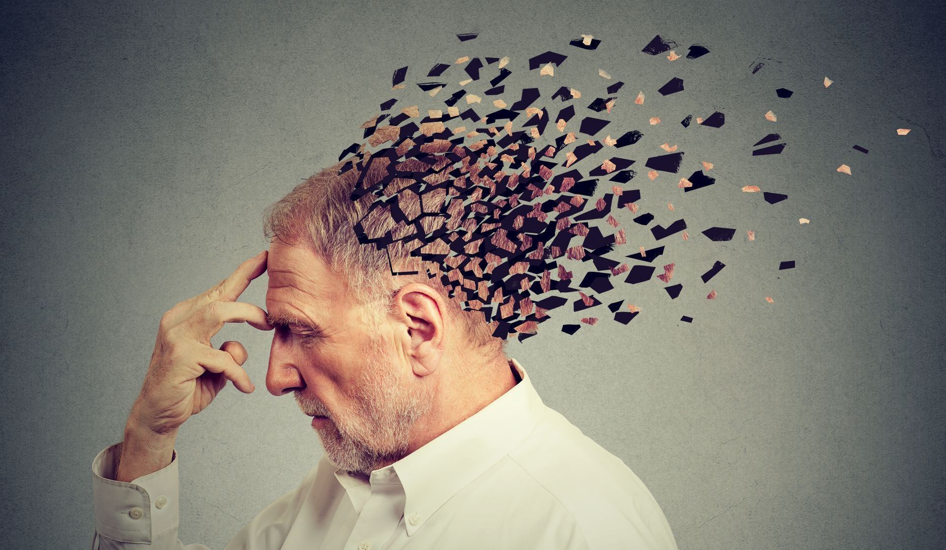 A man with a gray beard is holding his head and his hair is flying out of his head.