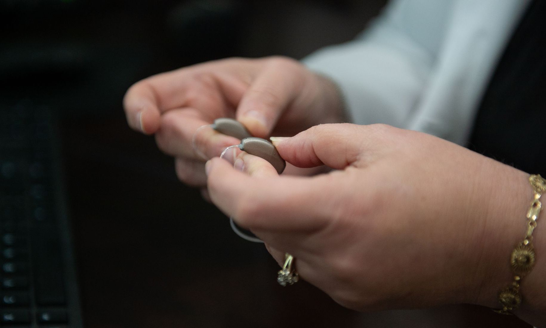 A woman is holding a pair of hearing aids in her hands.